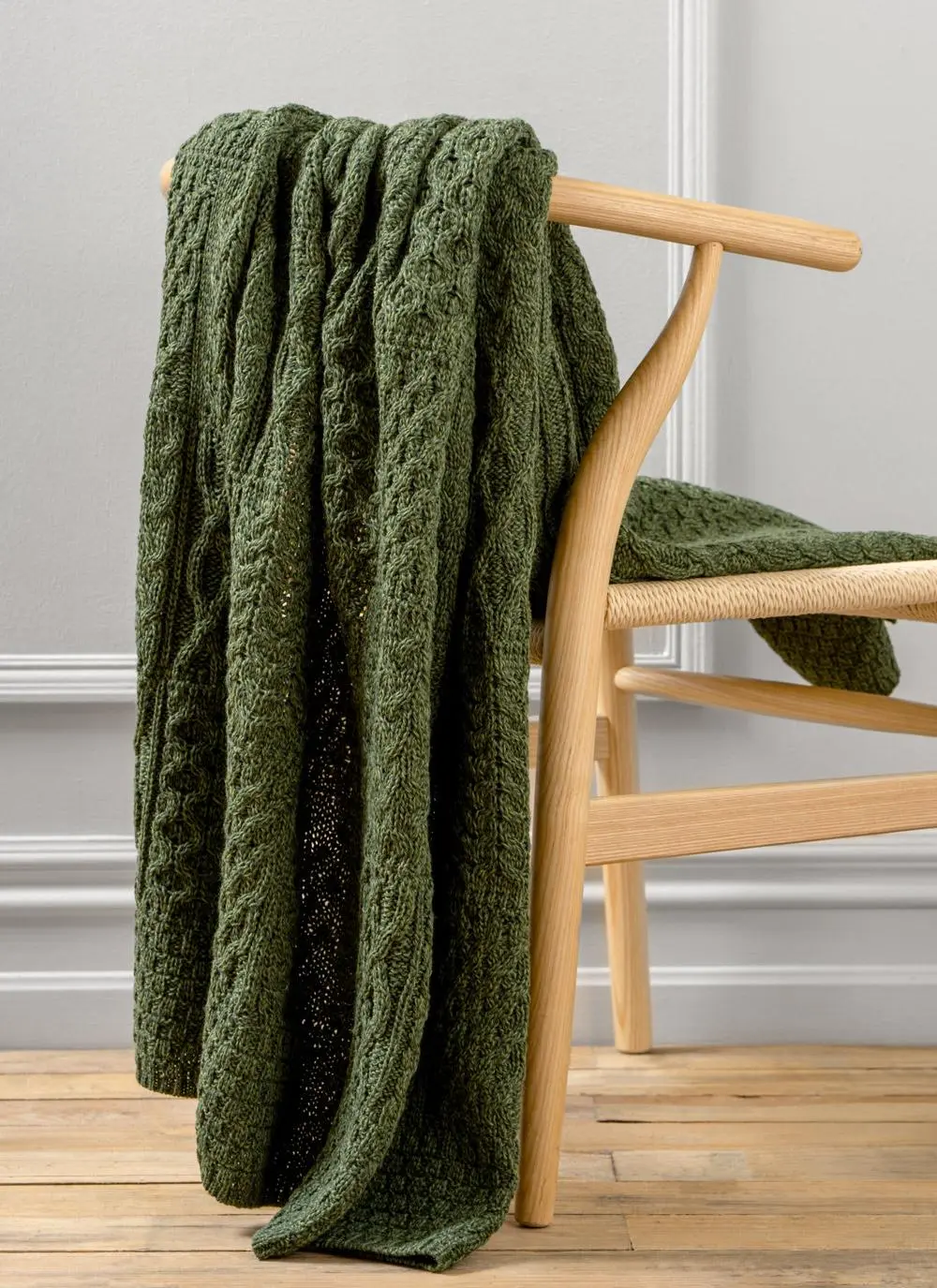 Dark green Aran throw draped across wooden chair